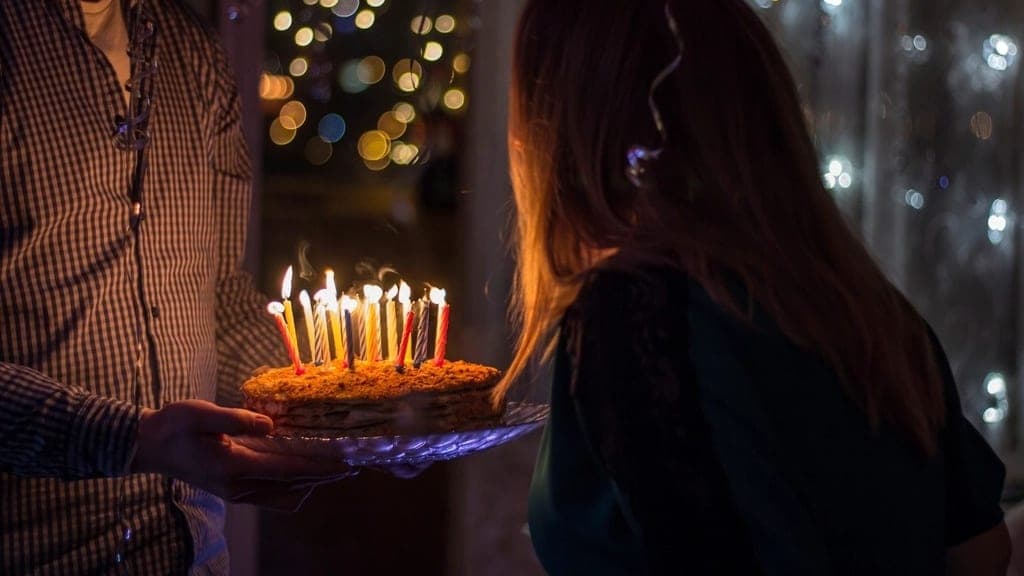 Someone carrying a birthday cake lit with candles
