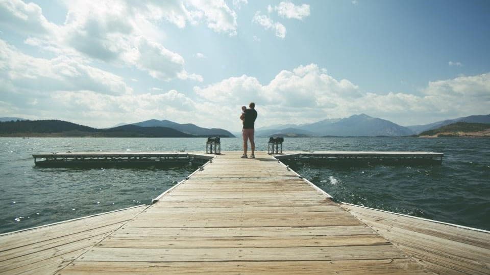 An adult and a child at the end of a long wooden pier