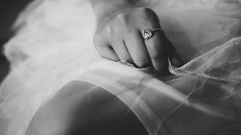 A hand wearing an engagement ring, in black and white