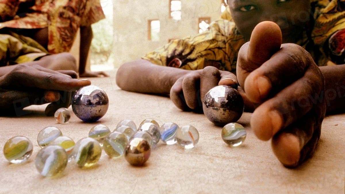 Children’s hands over a scatter of glass marbles